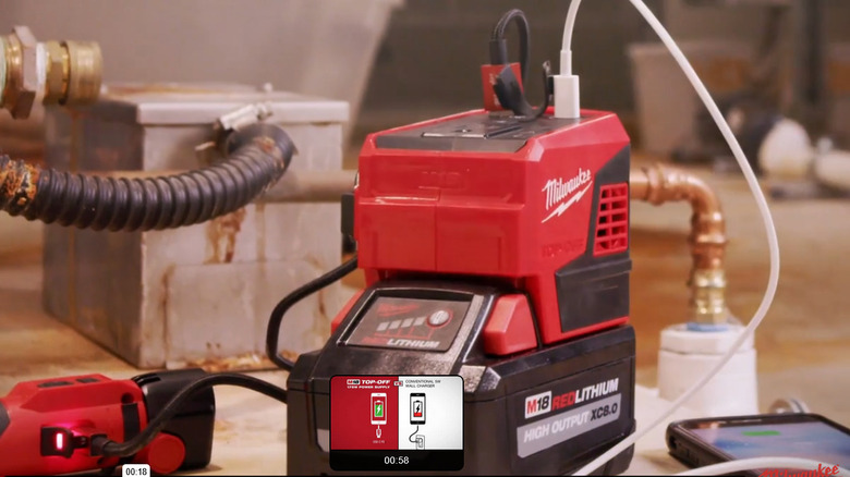 A Milwaukee M18 Top-Off 175W Power Supply charging multiple devices through its USB and AC ports.