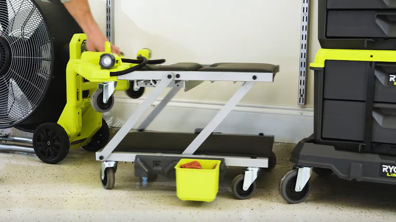 A black and neon green Ryobi 18V ONE+ Dual Function Lighted Creeper/Seat in a garage workshop.
