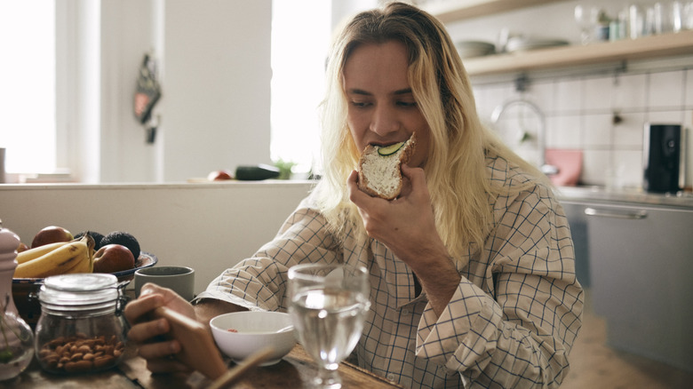 A woman eating in the kitchen.