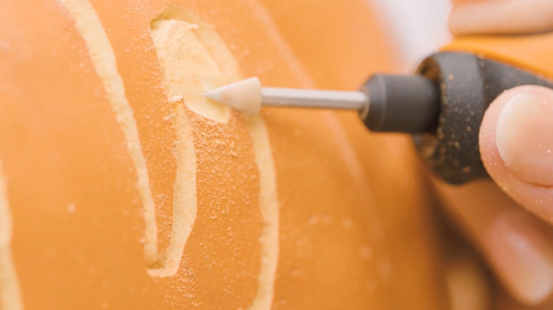 A rotary tool carving designs into pumpkins