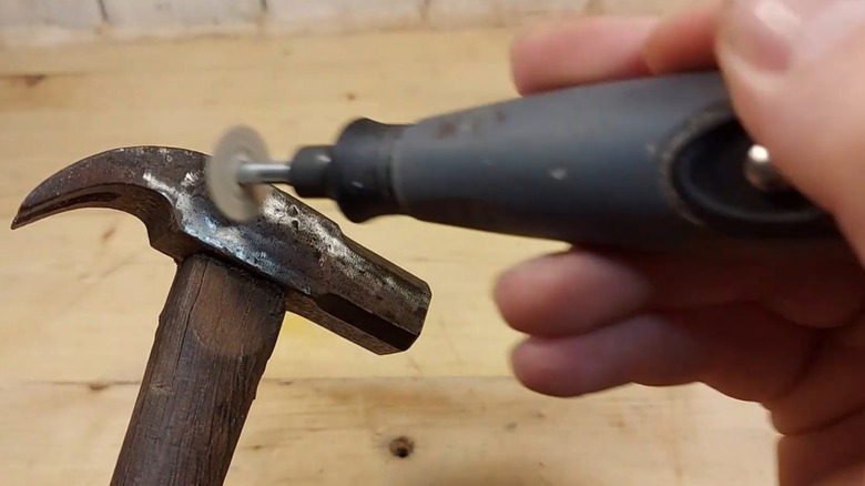 A rotary tool being used to clean rust from a hammer