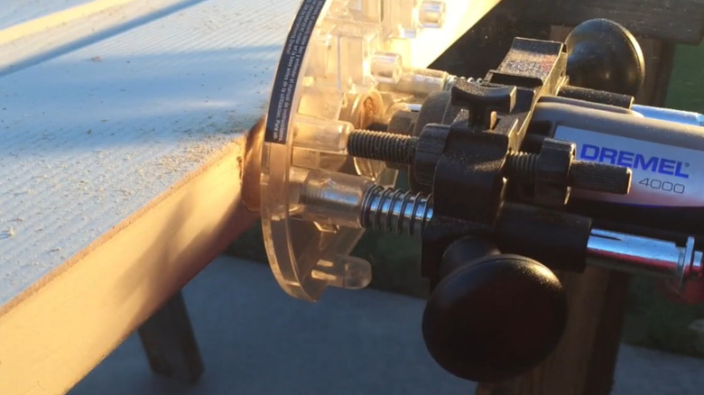 A Dremel rotary tool cutting hinges in a door