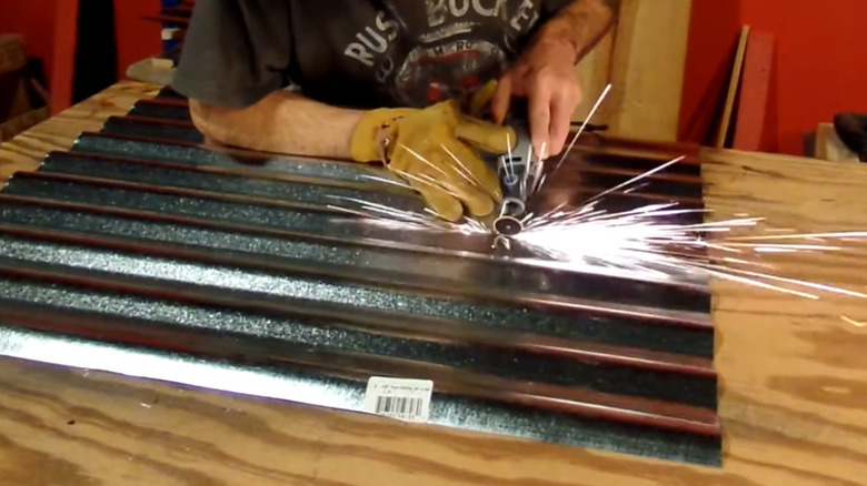 A person cutting thin sheet metal with a rotary tool