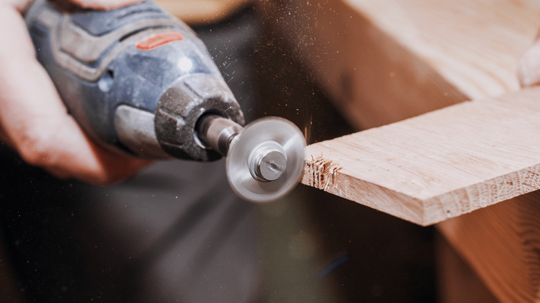 A rotary tool cutting into a wooden plank