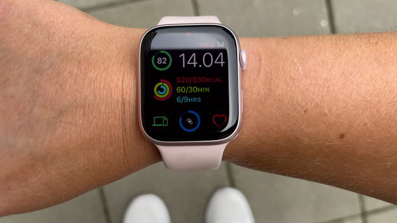 Person holding up Apple Watch while taking a walk outside