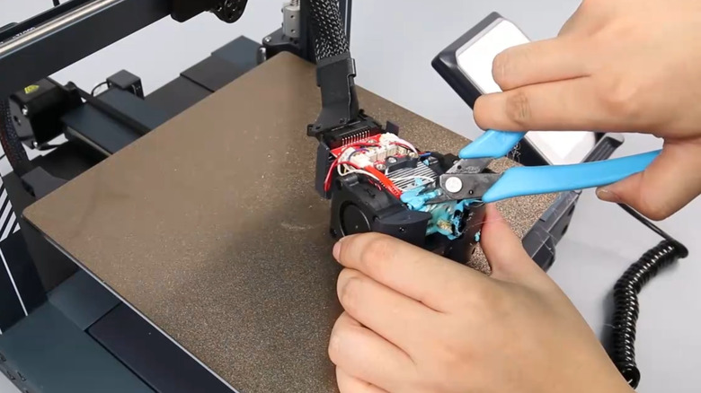 Cleaning a nozzle clog with pliers