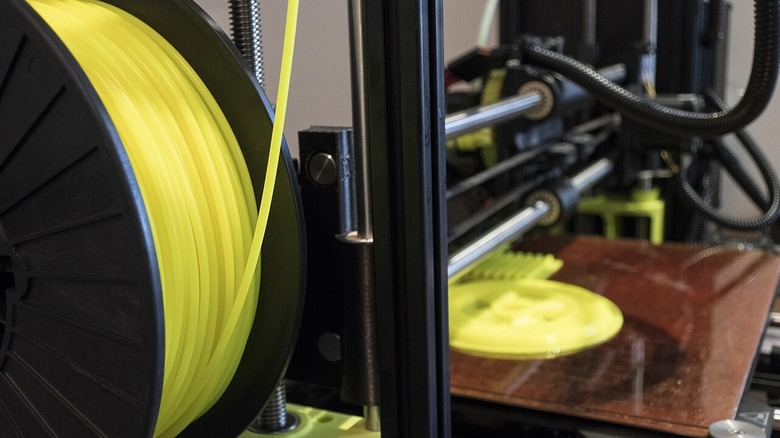 Closeup of 3D printer with filament and cables visible