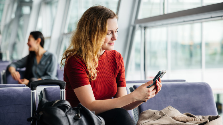 Woman in airport holding telephone