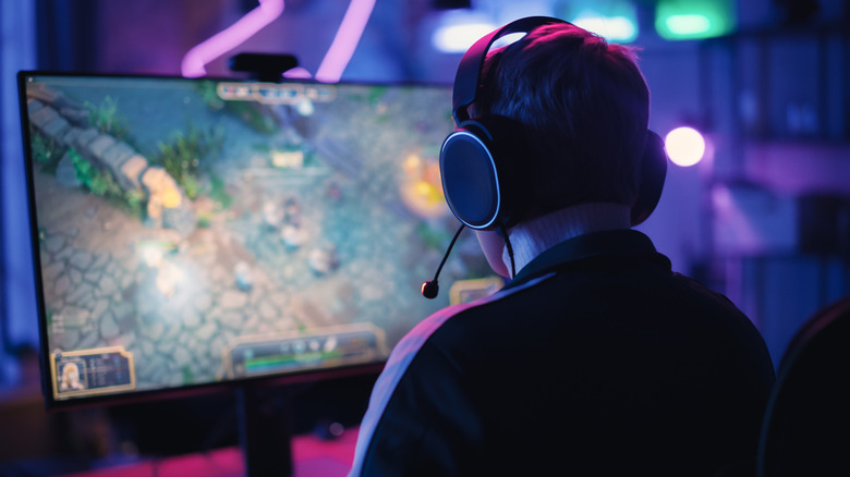 A person playing a game on a PC while wearing headphones