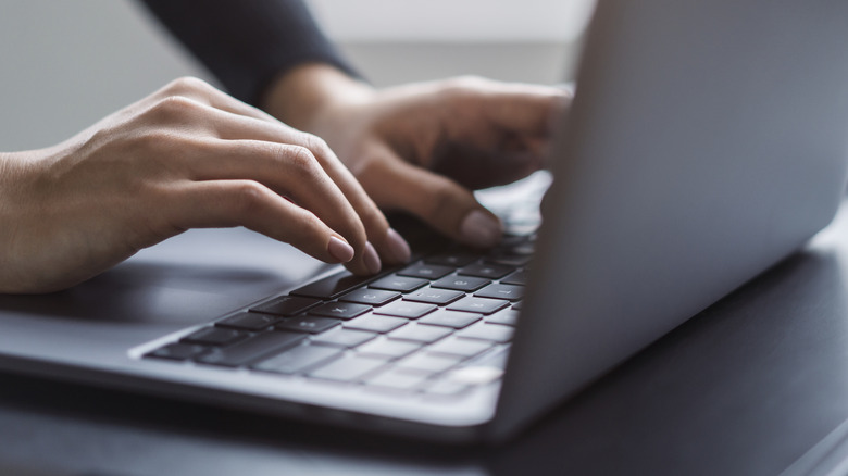 A person out of frame typing on a laptop