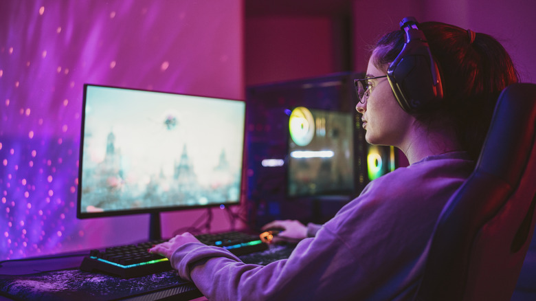 A person playing a game on a PC in a dimly-lit room