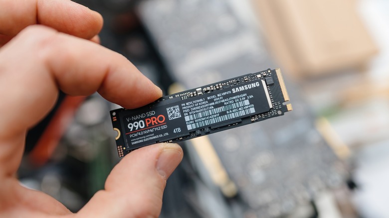 A Samsung 990 PRO NVMe SSD stick held between two fingers