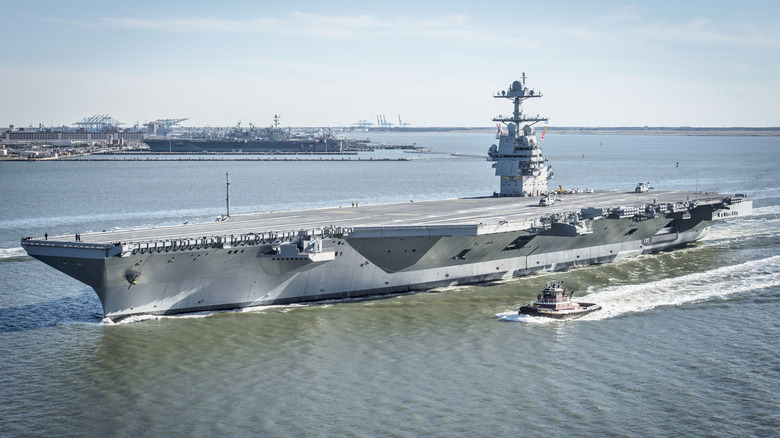 US Navy aircraft carrier USS Gerald Ford (CVN 78) seen from port side accompanied by a tugboat