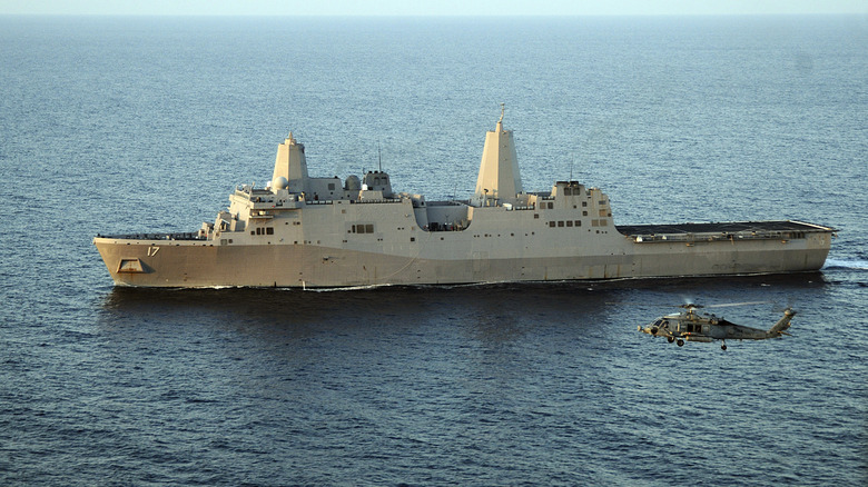 LPD-class USS San Antonio seen from port side accompanied by a helicopter