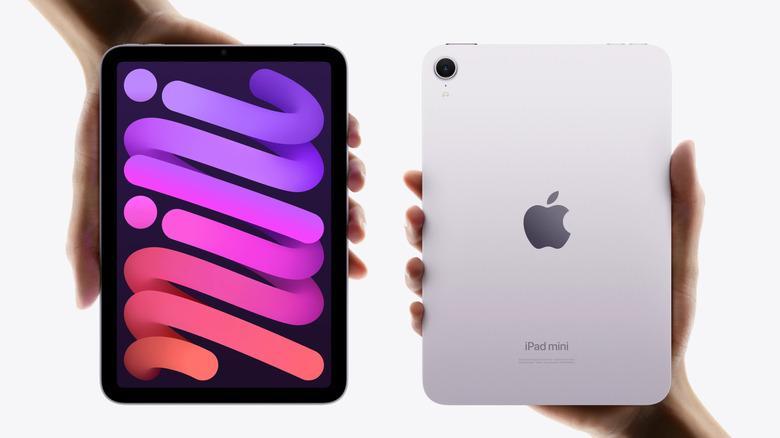 Two hands holding two iPads on a white background.