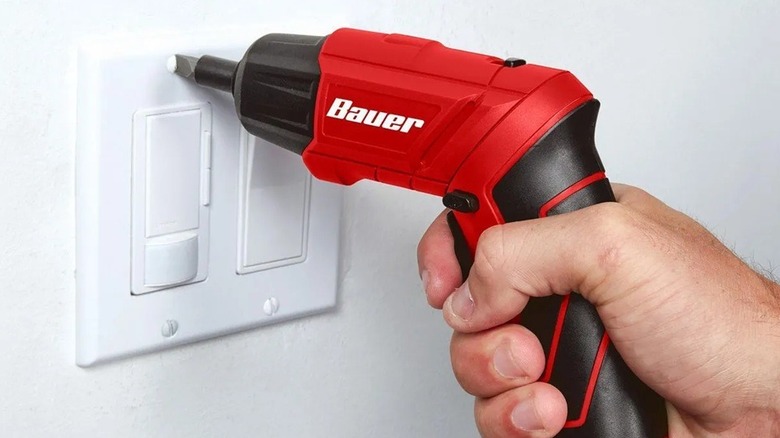 Person using a Bauer powered driver to screw in a switch plate