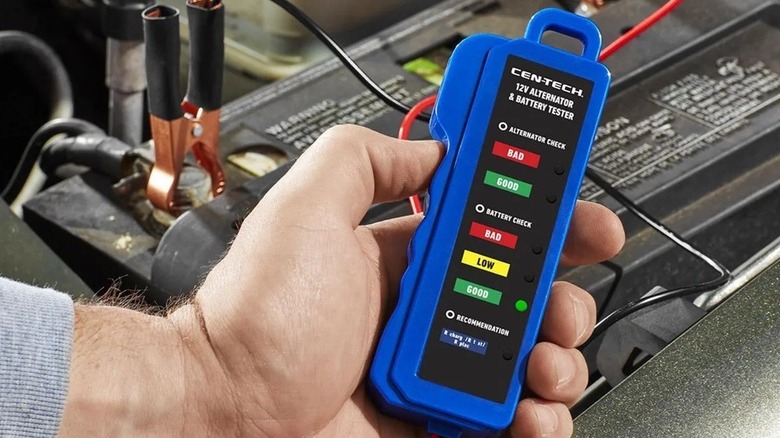 Person using battery and alternator checker on a car battery