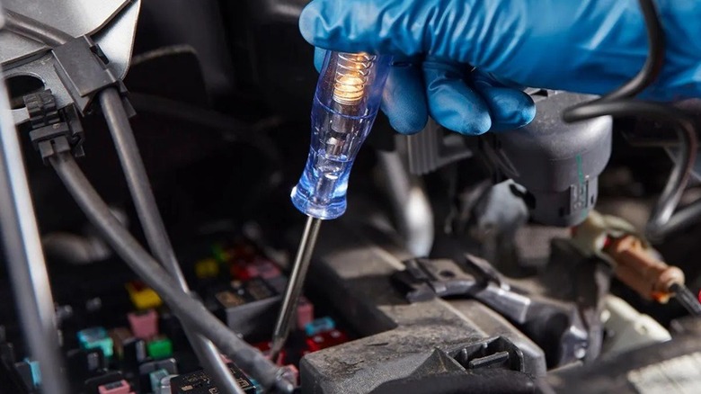 Person using a circuit tester to test a vehicle fuse