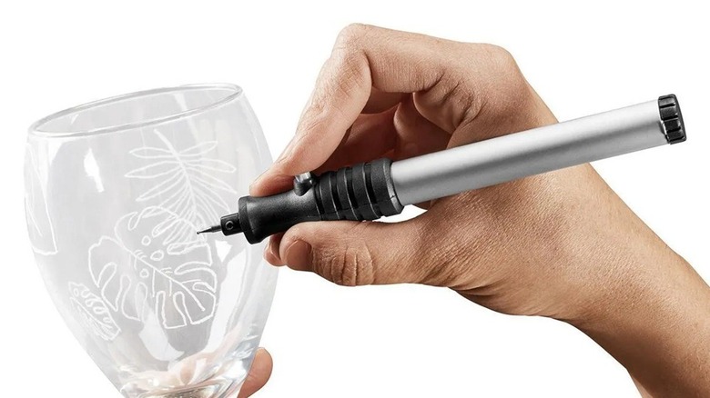 Person using micro-engraver on a large wine glass