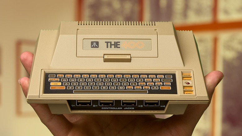 The Atari 400 Mini console held by a person in one hand.