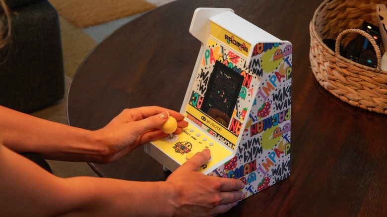 A person playing with the Pac-Man Mighty Player on a desk.