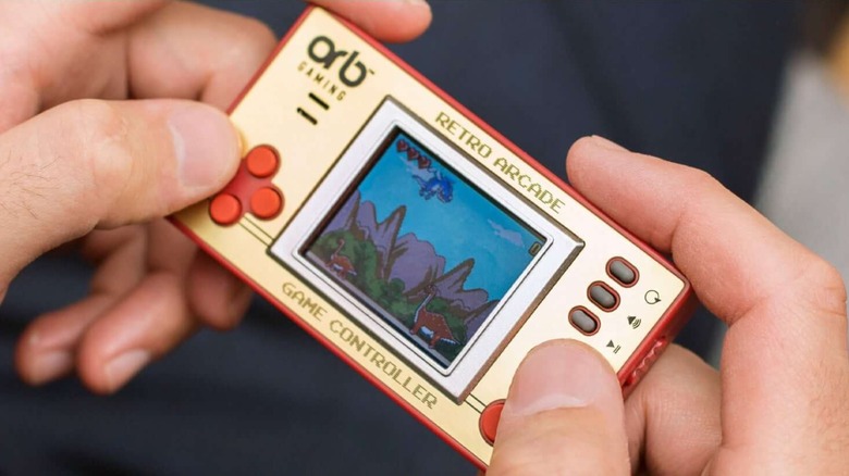 A person plays with the Thumbs Up! Orb retro handheld gaming console.