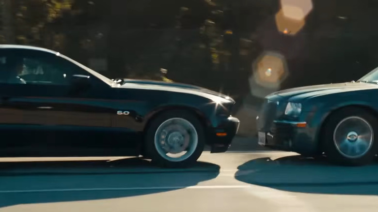 A black Mustang 5.0 S197 driving in reverse while a silver Chrysler 300C attempts to catch up.