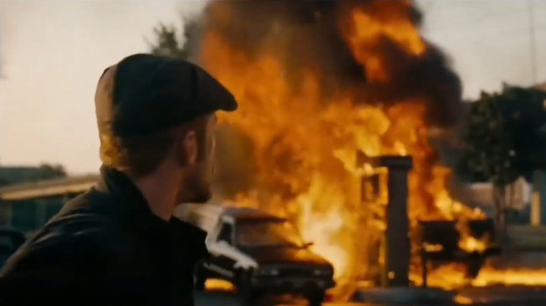 Steve McKenna (Ben Foster) turning and looking back at an exploded vehicle at a gas station in "The Mechanic" from 2011.