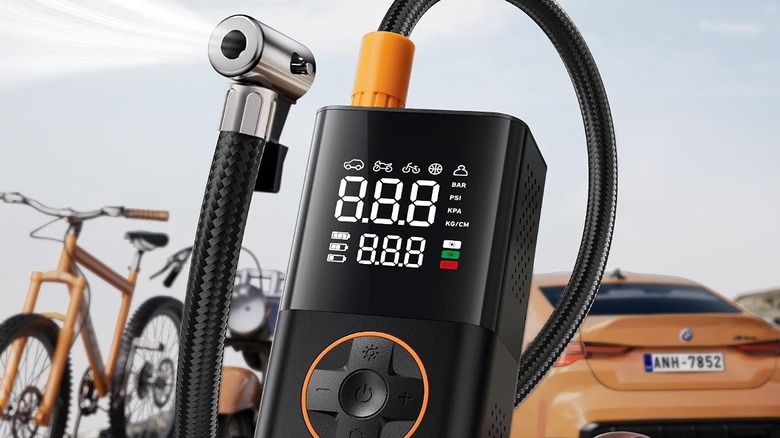 AstroAI L7 portable tire inflator in front of a bicycle and a sedan