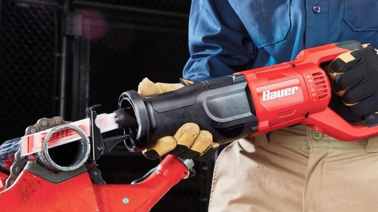 Person cutting a pipe with a Bauer reciprocating saw