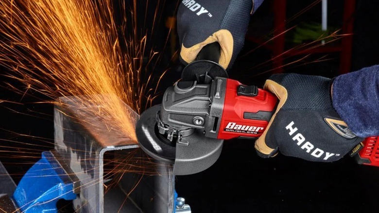 Person grinding a steel box section edge with a Bauer angle grinder