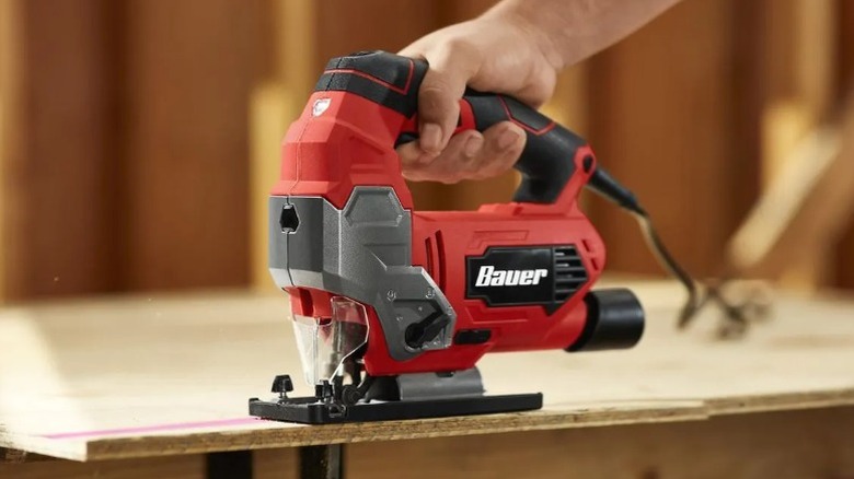 Hand holding a Bauer jigsaw cutting plywood