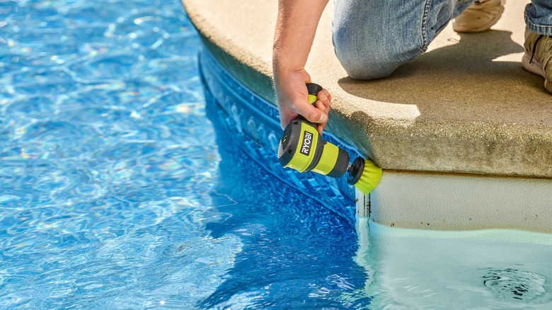 Ryobi USB Lithium Telescoping Power Scrubber cleaning a pool edge