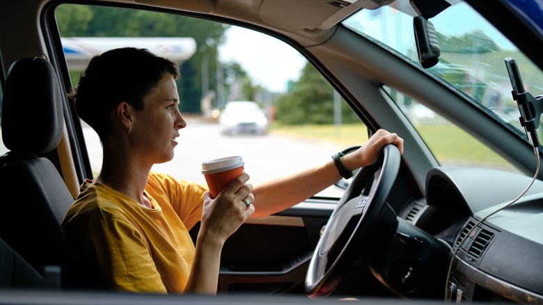 Person sitting in a car with a hand on the steering wheel