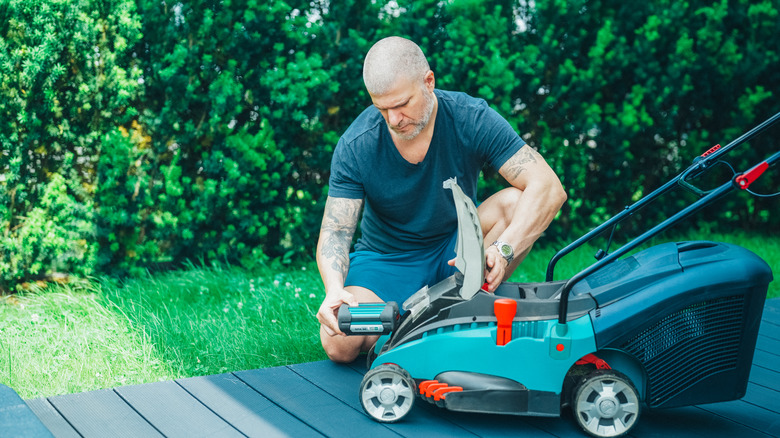 A man loading a battery into lawn mower