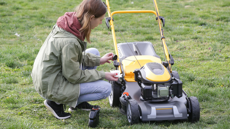A home landscaper adding oil to a gas-powered lawn mower