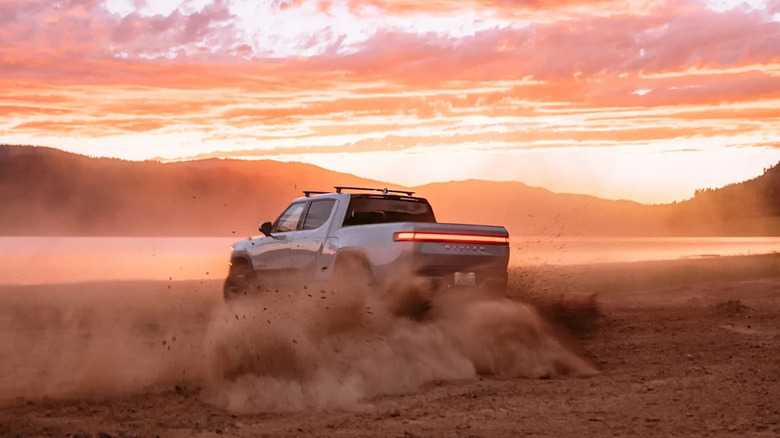 2025 Rivian R1T drifting on a dirt road during sunset