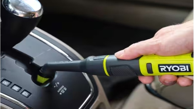 Hand using a crevice tool to clean a car gear shifter