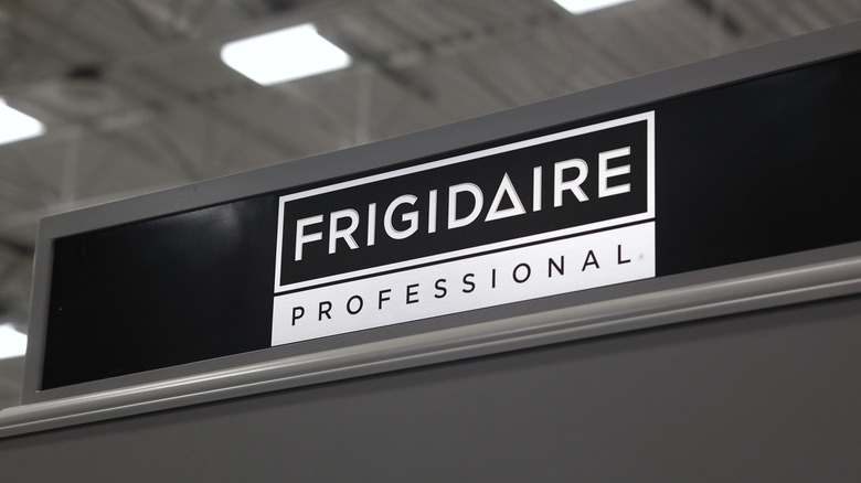 A store sign with the Frigidaire logo against an industrial ceiling backdrop.