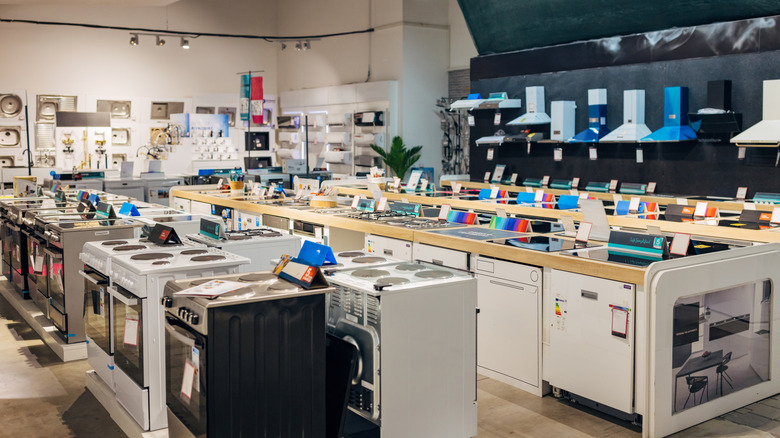 A wide interior view of a home appliance showroom displaying rows of modern cooktops, ovens, and kitchen hardware.