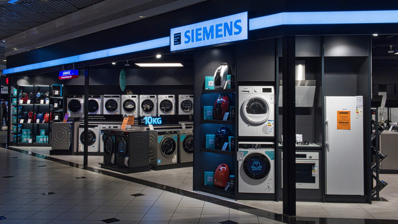 An appliance showroom display featuring Siemens washing machines, refrigerators, and vacuum cleaners.
