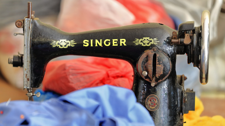 A vintage black Singer sewing machine on a table with blue fabric in the foreground.