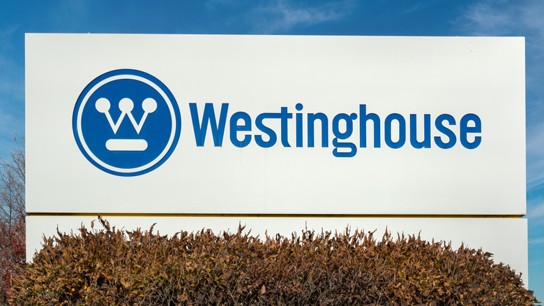 An outdoor corporate sign of the Westinghouse name and logo against a blue sky.