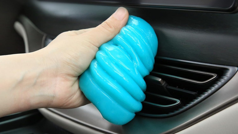 A person cleaning a car's AC vents using a cleaning gel
