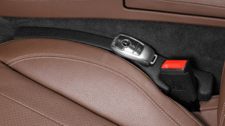 A car seat gap filler holding a car key on top