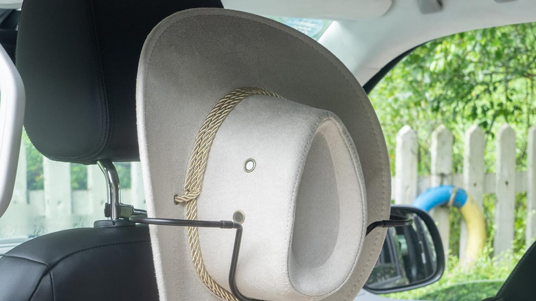A cowboy hat placed at the back of a car's neck rest