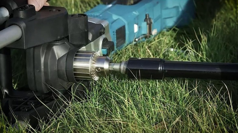 The earth auger drill bit adapter connecting the two pieces together while laying in the grass