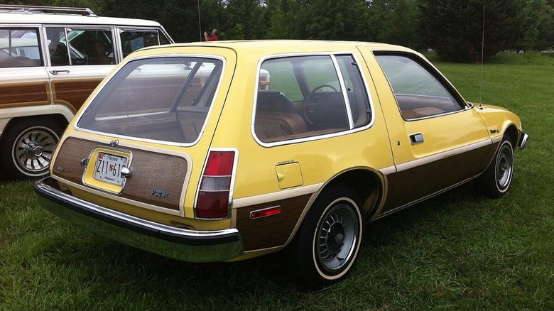 A yellow and brown AMC Pacer sitting in the grass