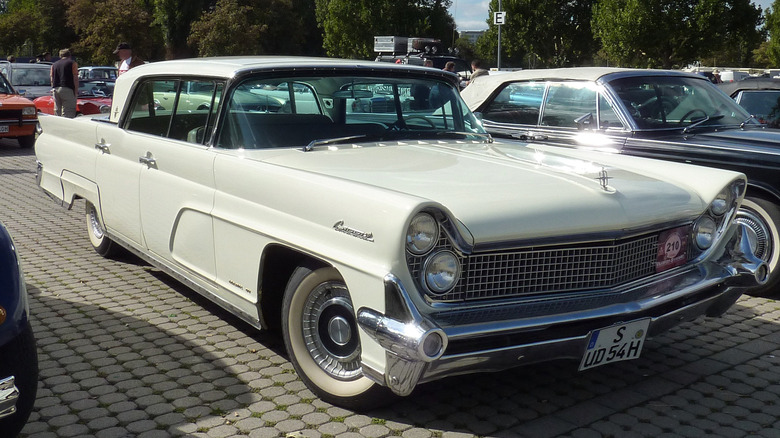 A white Lincoln Continental parked in a brick parking lot