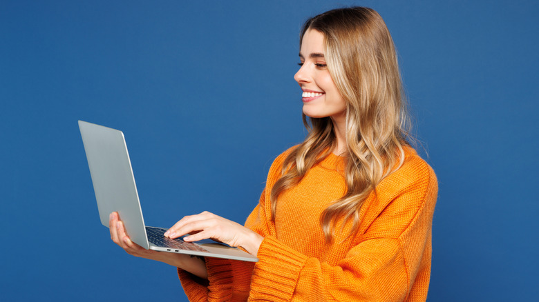 A standing woman holding a laptop